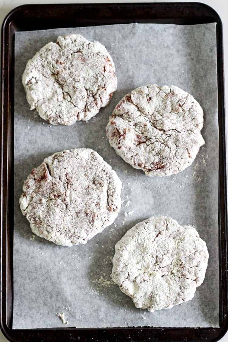 Homemade beef burger patties coated in flour on a baking tray