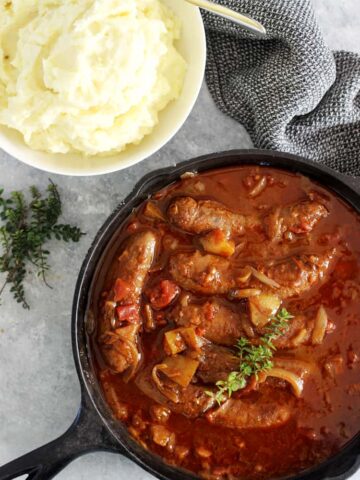 Pan of devilled sausages with mashed potato