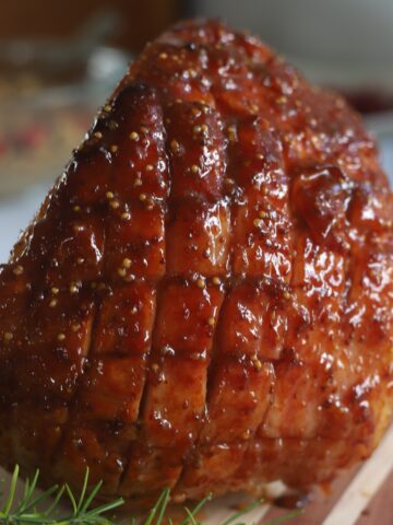 Apricot glazed ham on wooden board with rosemary